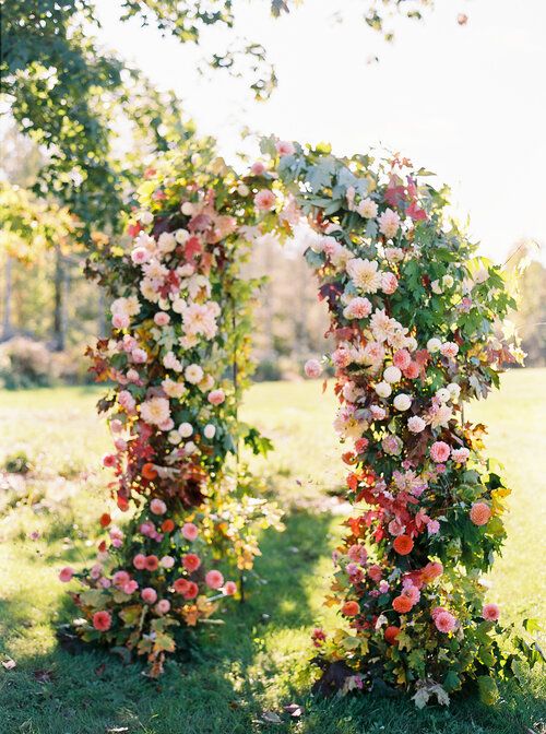 a summer wedding arch with light pink, blush, red, pink blooms, greenery is a very beautiful and lush idea for a bold wedding