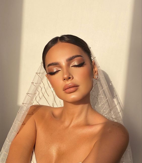 a bold bridal smokey eye makeup with shiny lilac smokeys, a glossy nude lip, a touch of blush and highlighter