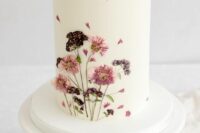 33 a white buttercream wedding cake with pink and purple pressed flowers on it is a cool and chic idea for a summer boho wedding