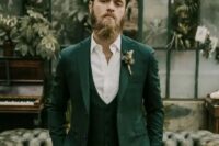 33 an elegant groom wearing a green three-piece suit, a white shirt and a green and white boutonniere looks chic