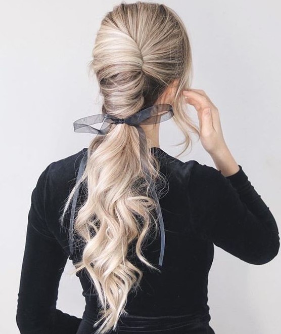 a gorgeous low chignon going into a long wavy ponytail and a sheer and etherel grey ribbon with a bow
