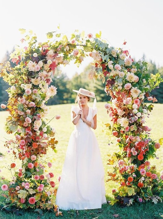 a jaw-dropping wedding arch with some foliage, pink, blush, red and neutral blooms all over is amazing for a bright summer wedding