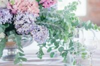 34 a relaxed pastel spring wedding tablescape with blue and pink hydrangeas, lilac and greenery and a light blue napkin