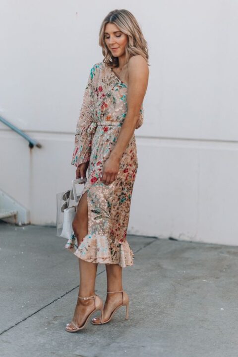 a tan one shoulder midi dress with a slit and a long sleeve, tan shoes and a white bag compose a lovely look for a summer wedding