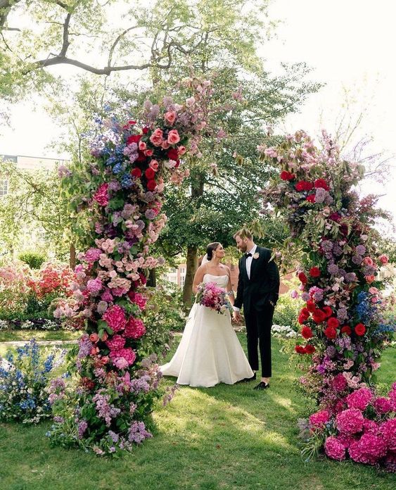 a bold wedding altar with light and hot pink, lilac, blue and purple and red blooms plus some greenery is amazing for a jewel-tone wedding