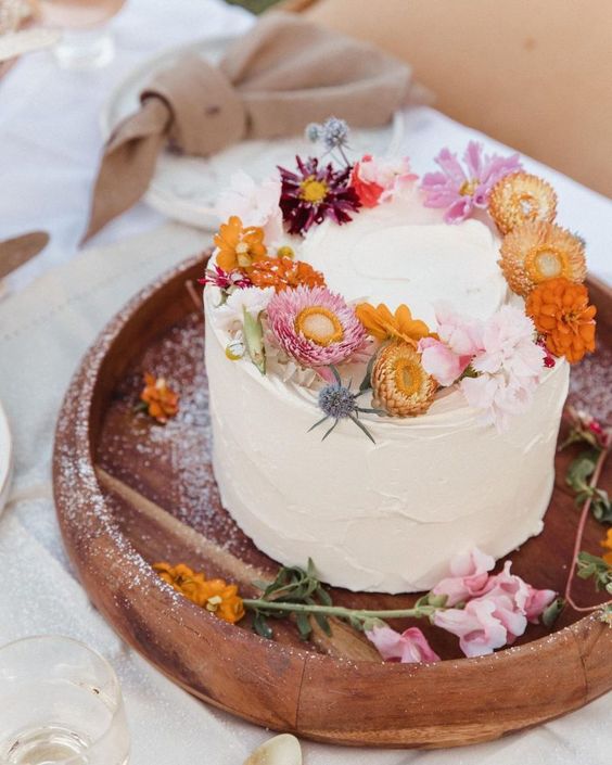 a white textural buttercream wedding cake topped with bold dried blooms and thistles is a catchy idea for a summer wedding