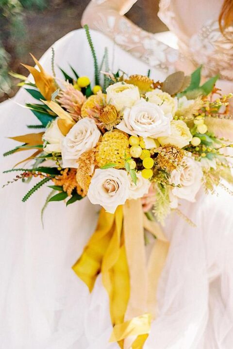 a bright wedding bouquet of neutral and yellow blooms, with twigs, greenery and berries for a summer bride