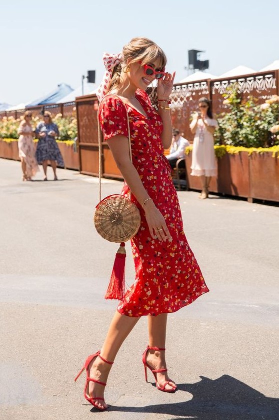 a vintage styled red floral midi dress with short sleeves and a V neckline, red heels and a straw bag