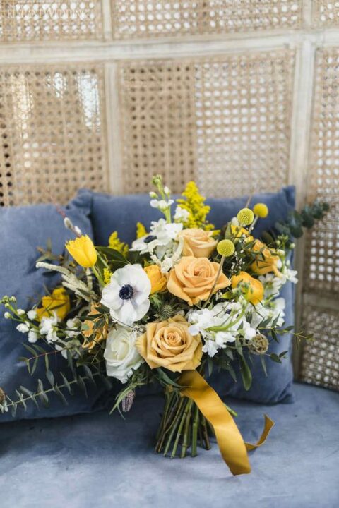a bright yellow wedding bouquet with various blooms, billy balls, some greenery and ribbons