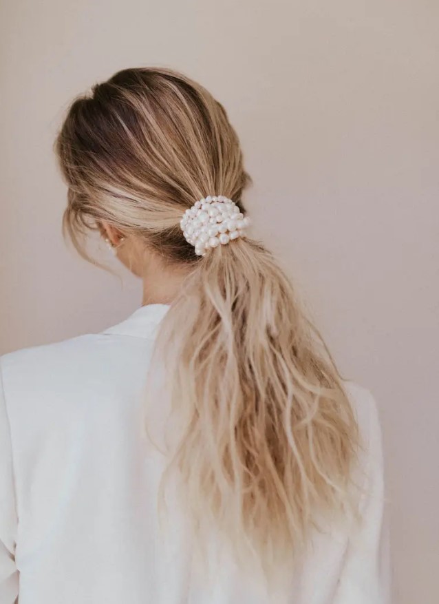 a low and messy ponytail wrapped up in pearls is a chic idea for a modern or minimalist bride