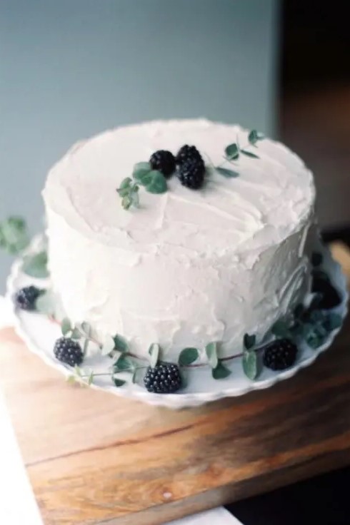 a white textural wedding cake topped with blackberries and fresh greenery is a cool and lovely solution for a fall wedding