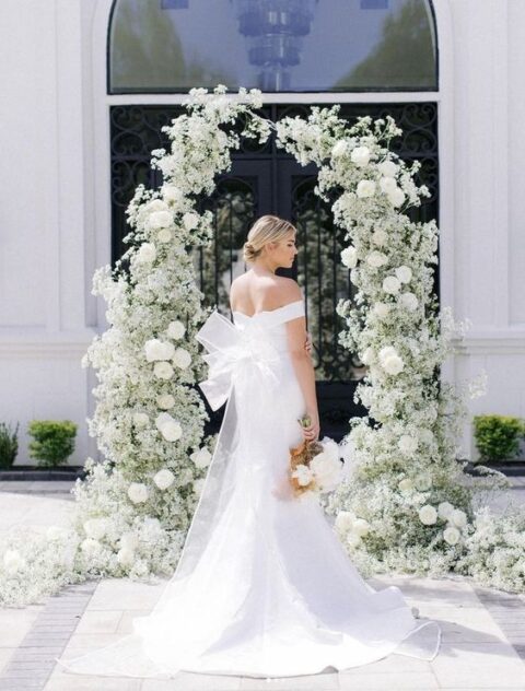 a lovely white wedding arch composed of baby’s breath and roses is a gorgeous and luxurious idea for a summer wedding