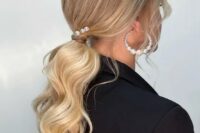 38 a low ponytail with waves, locks framing the face, some pearl pins and pearl earrings is a chic idea