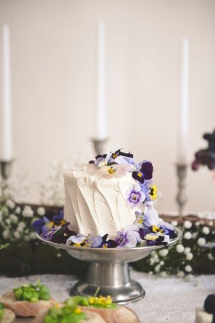 a white textured buttercream wedding cake topped with pansies is an ultimate summer wedding idea