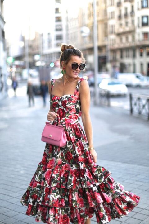 an A-line floral midi dress with a corset, thick straps and a ruffle tiered skirt, a pink bag and green earrings