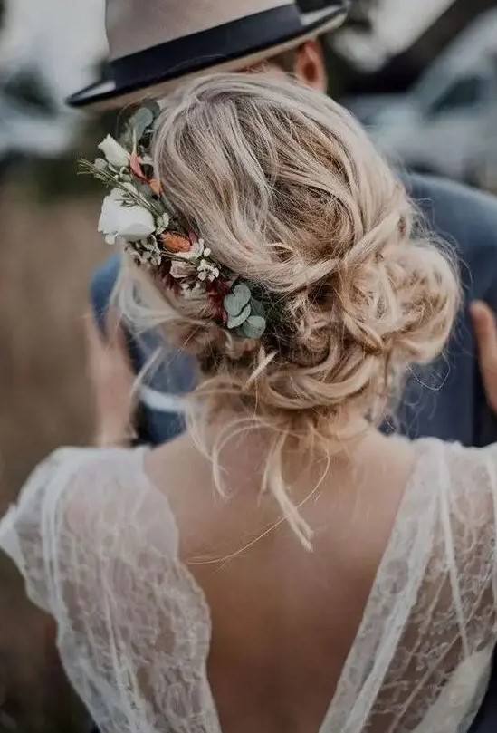  messy and loose wedding low updo with waves and locks down and with a floral accent - neutral and blush blooms and greenery