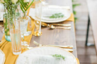 39 a chic and bold wedding tablescape with a yellow runner and napkins, with gold cutlery, white blooms and greenery is a vibrant idea