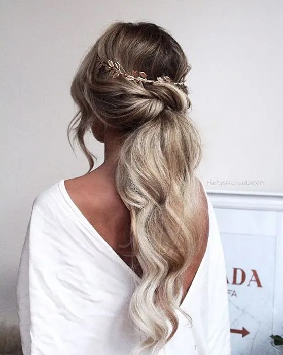 a low twisted textured ponytail with waves, locks down and a hair vine looks very romantic