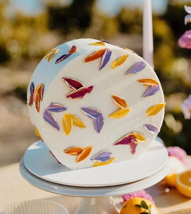 a white top forward wedding cake decorated with colorful petals is a gorgeous solution for a bright and fun summer wedding