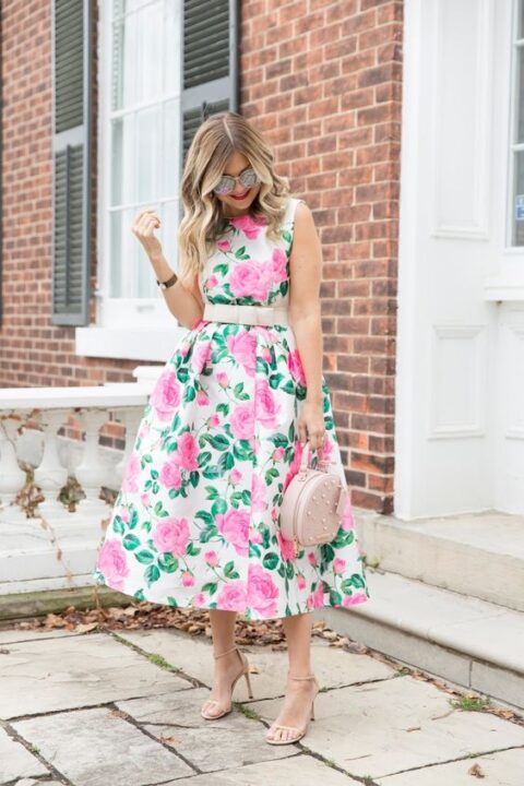 an A line hot pink floral midi dress with no sleeves and a blush sash, with nude shoes and a nude pearl bag for a retro inspired wedding