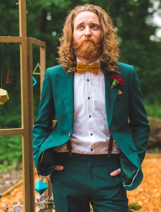 an emerald suit, a white shirt with black buttons, suspenders and a mustard bow tie to pull off a jewel color palette