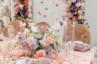 40 an adorable pastel wedding tablescape with a pink table runner, lilac napkins, lilac and peachy blooms and lilac candles