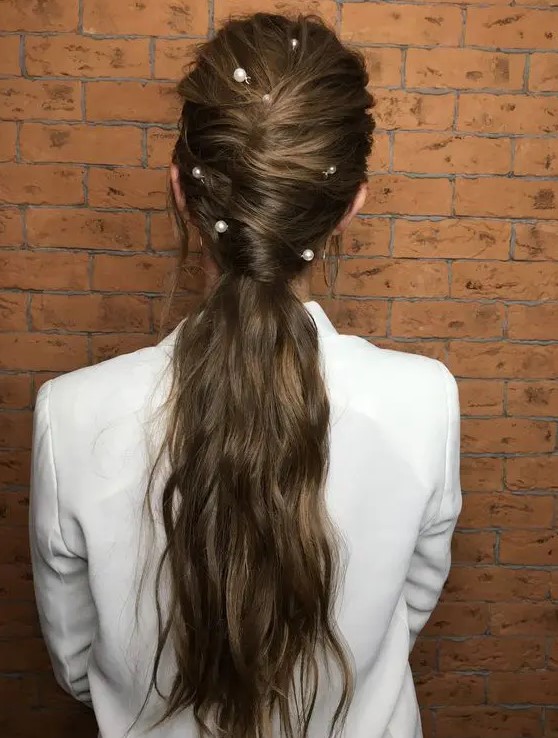 a wavy twisted low ponytail with some locks down and large pearl pins for a bolder accented look