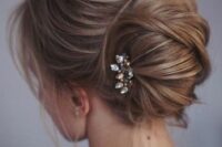 42 a messy twisted chignon with locks down and a small rhinestone hairpiece on one side