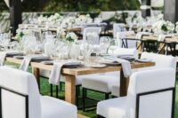 42 a modern lux wedding reception space with wooden tables, neutral linens, white blooms and candles plus chic upholstered chairs