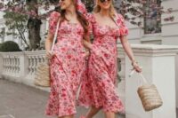 42 gals wearing the same pink floral midi dresses with red prints, orange shoes, straw bags for a spring wedding