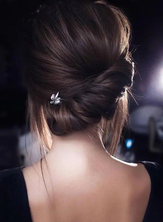 a modern low updo with a twisted low chignon and a voluminous top plus some locks down is a stylish idea