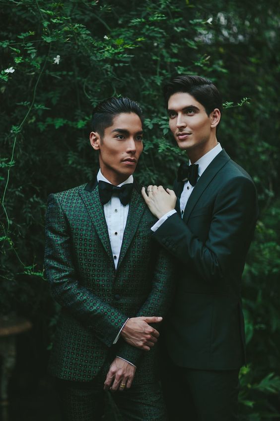 beautiful green pantsuits, a dark green one and a green printed one, white shirts and black bow ties for a cohesive couple's look