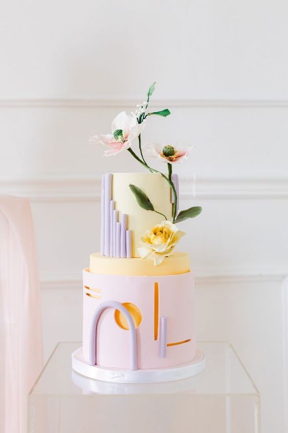 a catchy pastel spring wedding cake with a blush and yellow tier, lilac details and some goemetry plus sugar blooms