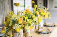 44 a refined wedding tablescape with yellow and rust linens, with bold yellow blooms, woven chargers and chic vases