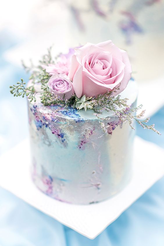 a light mint blue wedding cake with pink and blue touches and pink roses and greenery on top is gorgeous for spring