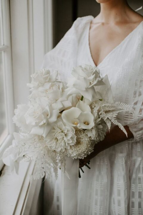 a refined wedding bouquet composed of only white blooms – roses, calla lilies, dahlias and leaves is amazing for summer