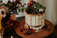 46 a chocolate naked wedding cake with caramel drip, fresh berries and dark blooms, macarons and greenery