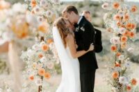 47 a chic and catchy wedding arch with white, blush ad orange blooms delicately covering the arch is a lovely and effortlessly chic idea