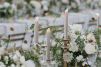 48 a romantic wedding table setting done with lush white and blush blooms and greenery, grey tall and thin candles, white porcelain and elegant glasses