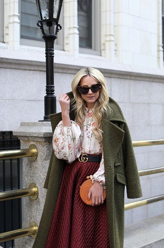 a floral blouse, a burgundy tweed A-line midi skirt, a green coat and a round orange bag