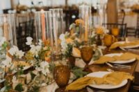 50 a stylish wedding tablescape with white and marigold blooms, mustard napkins, orange candles and amber glasses