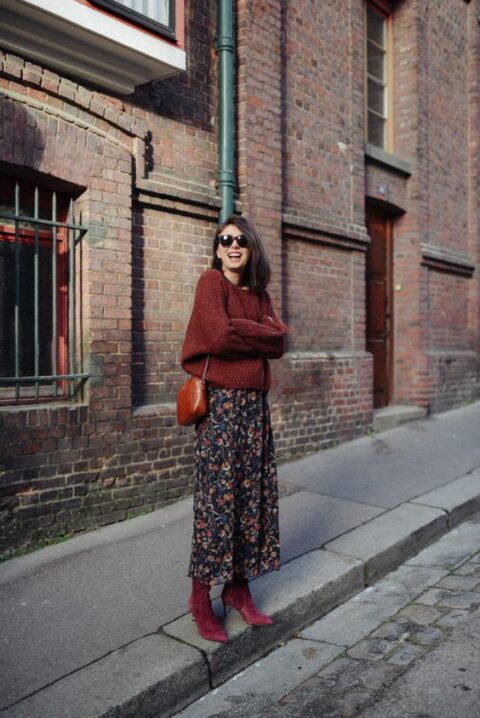 a pretty and casual fall wedding look with a burgundy oversized sweater, a navy midi skirt with colorful floral prints, purple booties and an amber bag