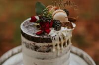 53 a pretty fall chocolate naked wedding cake with creamy drip, blackberries, macarons, figs, red blooms and a gold calligraphy topper