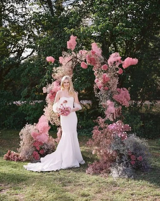 a modern pink wedding arch with pink and mauve blooms looks very eye-catchy and bright and adds color to the space