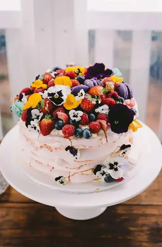a bright meringue wedding cake with pansies and fresh berries is a gorgeous idea for a colorful summer wedding, it looks very inspiring