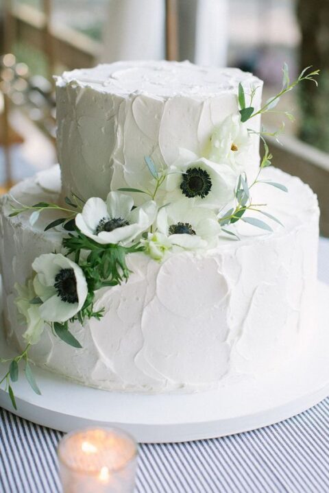 a white textural buttercream summer wedding cake decorated with white anemones and greenery is a cool idea to try