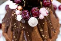 60 a chocolate bundt wedding cake with chocolate drip, gold leaf, fresh cherries, meringues and beads is a lovely and glam idea