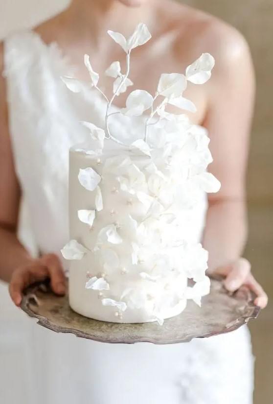 an ethereal white wedding cake decorated with beads and pearls plus white sugar leaves and petals is amazing