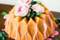 61 a creatively shaped bundt wedding cake with pink drip, pink blooms and greenery on top for a refined garden wedding