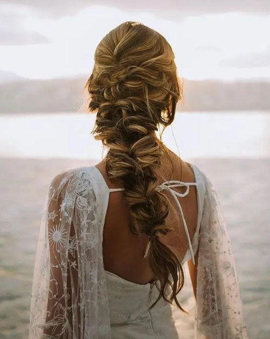 a boho twisted braid with some locks down and a volume on top is a messy and chic idea for a boho bride